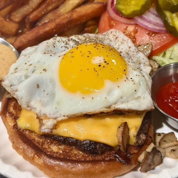 Harvey's burger with a fried egg, melted cheese, mushrooms, fries, and a side salad.