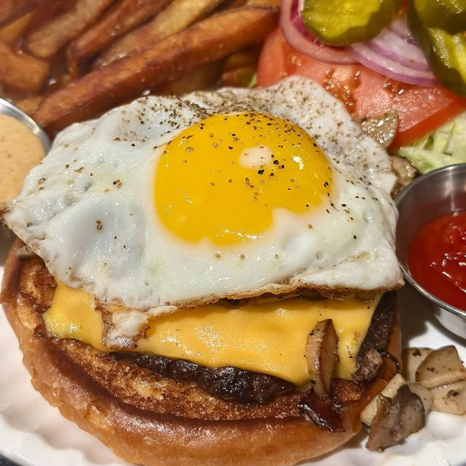 Harvey's burger with a fried egg, melted cheese, mushrooms, fries, and a side salad.