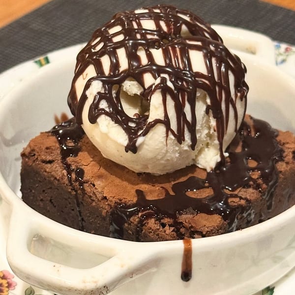 Harvey's warm chocolate brownie topped with vanilla ice cream and chocolate drizzle in a white bowl.