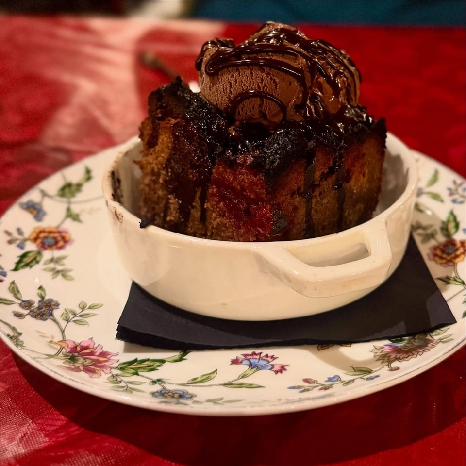 Harvey's chocolate bread pudding with chocolate ice cream and drizzle, served on a floral plate.