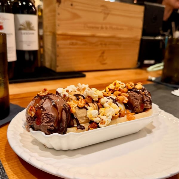 A banana split with chocolate and caramel ice cream, topped with popcorn and nuts.